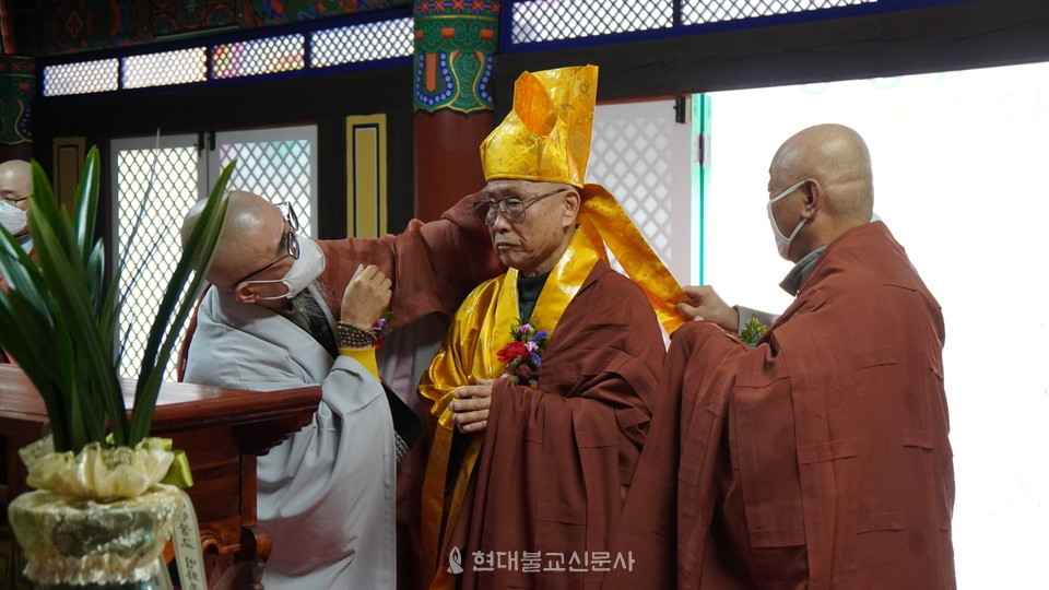 도선 스님이 종정추대위원장 보명 스님과 간사 서안 스님의 도움으로 금란가사와 비로관을 수하고 있다.