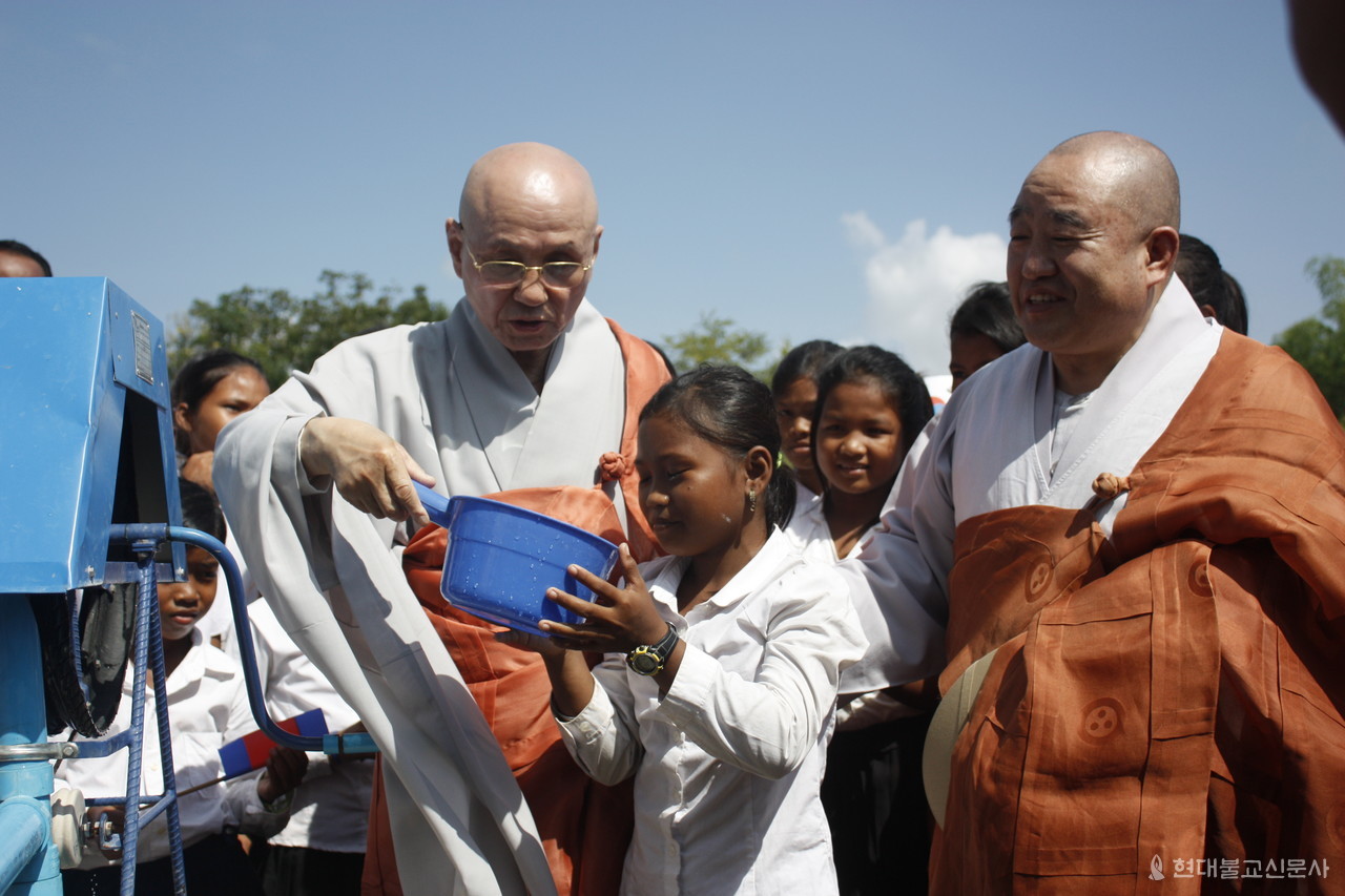 월주 대종사가 상좌인 조계종 총무원장 원행 스님과 2013년 11월 생명의 우물 2000기 완공식에 참석해 현지 어린이에게 물을 건네는 모습.