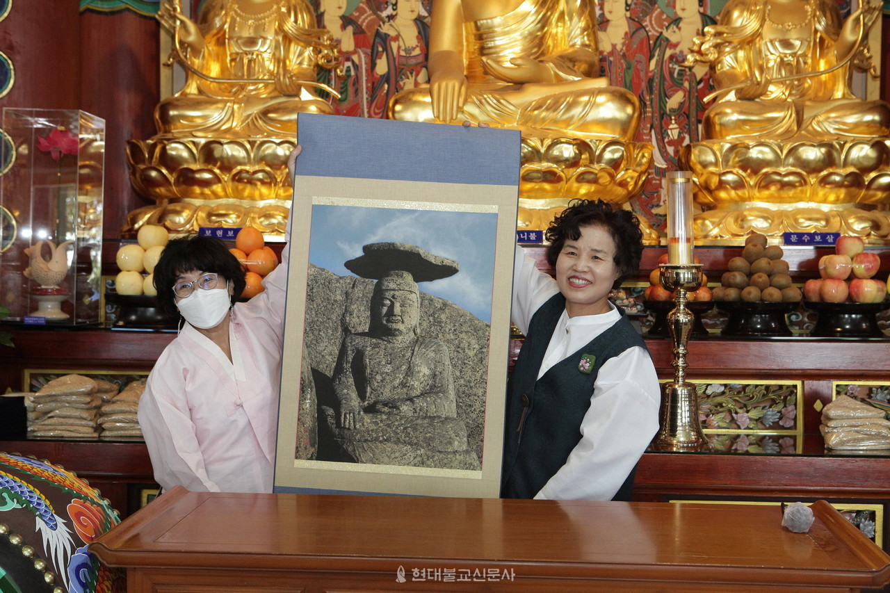 삼보회 활동을 지켜보고 후원한 한 불자가 정분남 회장에게 팔공산 갓바위 부처님 사진을 담은 족자를 전달하는 모습