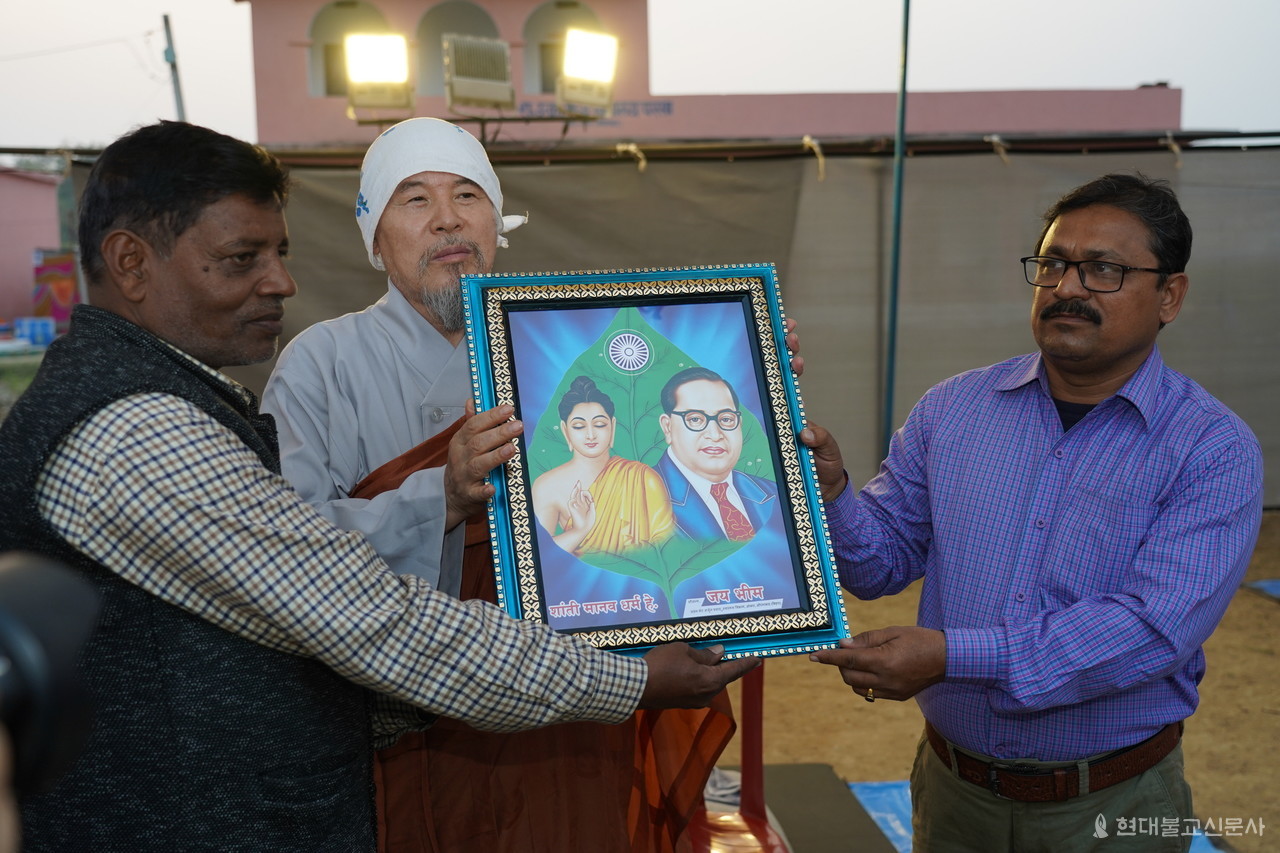 지역 주민이 회주 자승 스님에게 부처님과 암베르카르 박사가 함께 그려진 액자를 선물하고 있다.