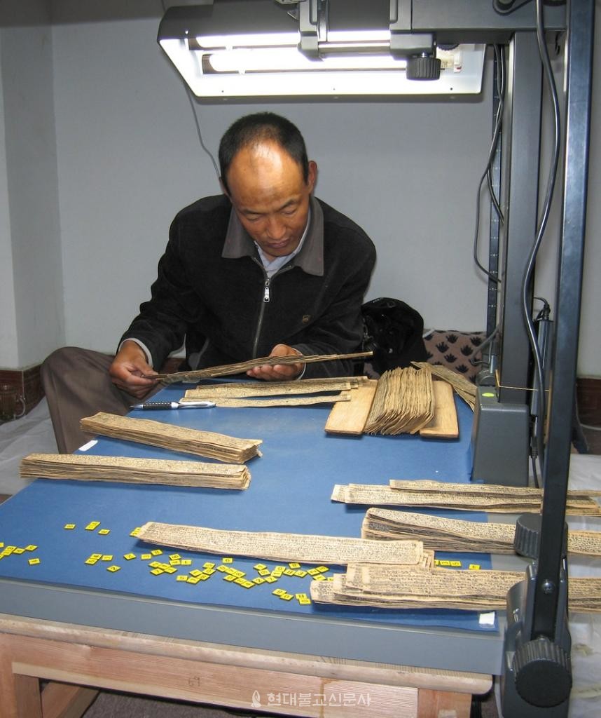 라싸의 티베트 박물관에서 규메출팀 팀장이 종려나무 잎 경전을 정리하고 있다. 사진출처=신화통신
