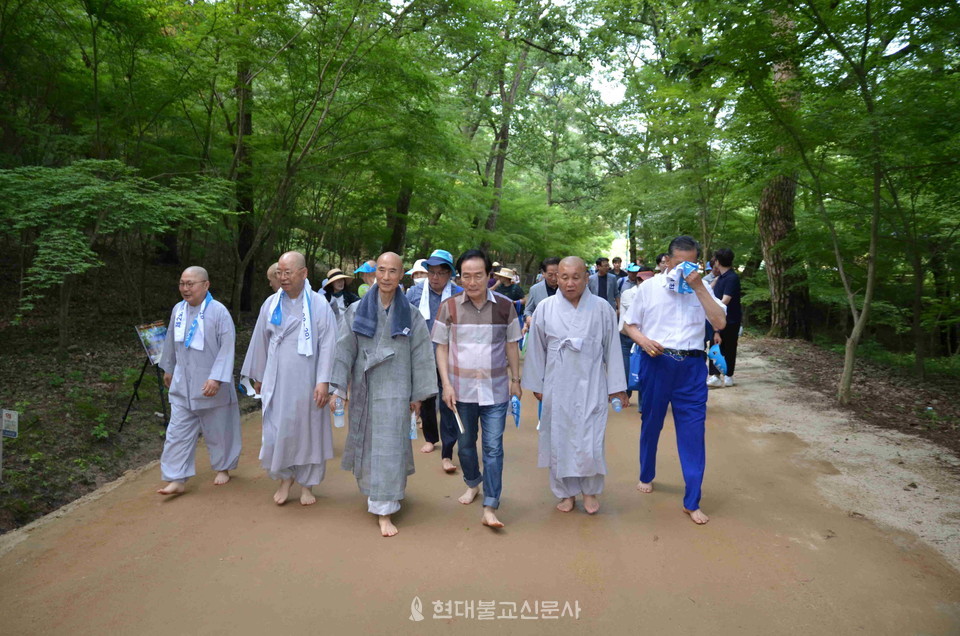 등운스님과 참가자들이 이야기를 나누며 맨발로 걷고 있다.