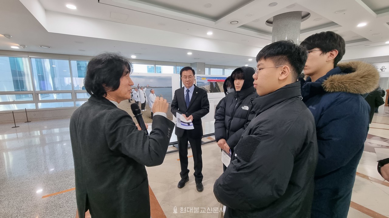 이재갑 작가가 전시 사진에 대해 설명하고 있다.  