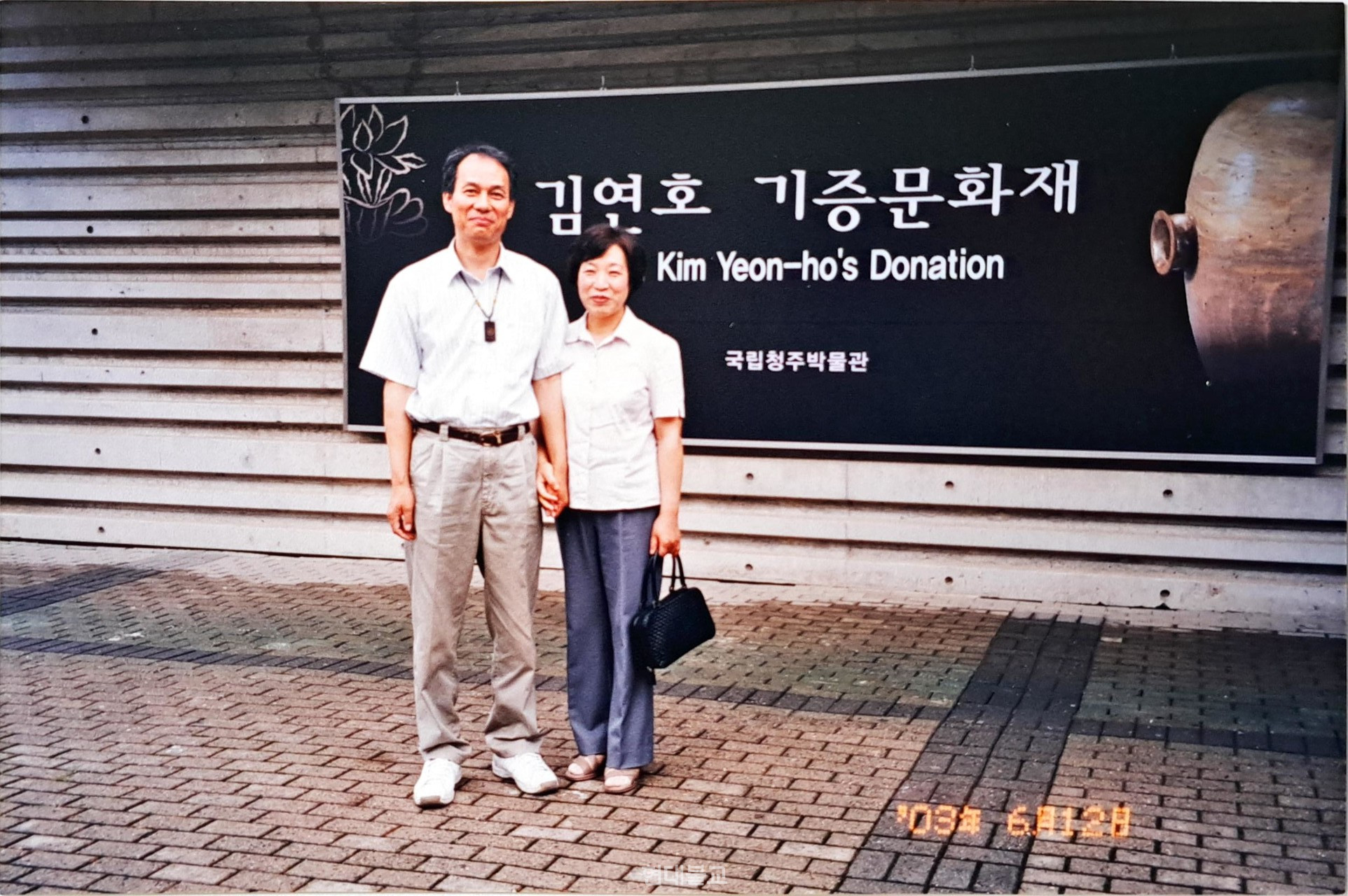 2003년 국립청주박물관에서 열린 ‘김연호 기증문화재’ 전시회 현수막 앞에서 김연호 회장이 부인과 기념촬영을 하고 있다.