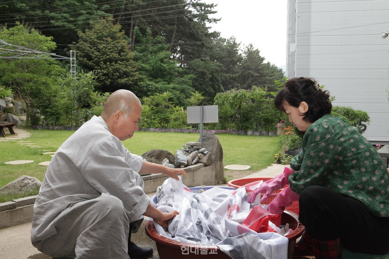  정찬 스님이 신도와 함께 가방으로 거듭날 폐현수막을 세탁하고 있다.