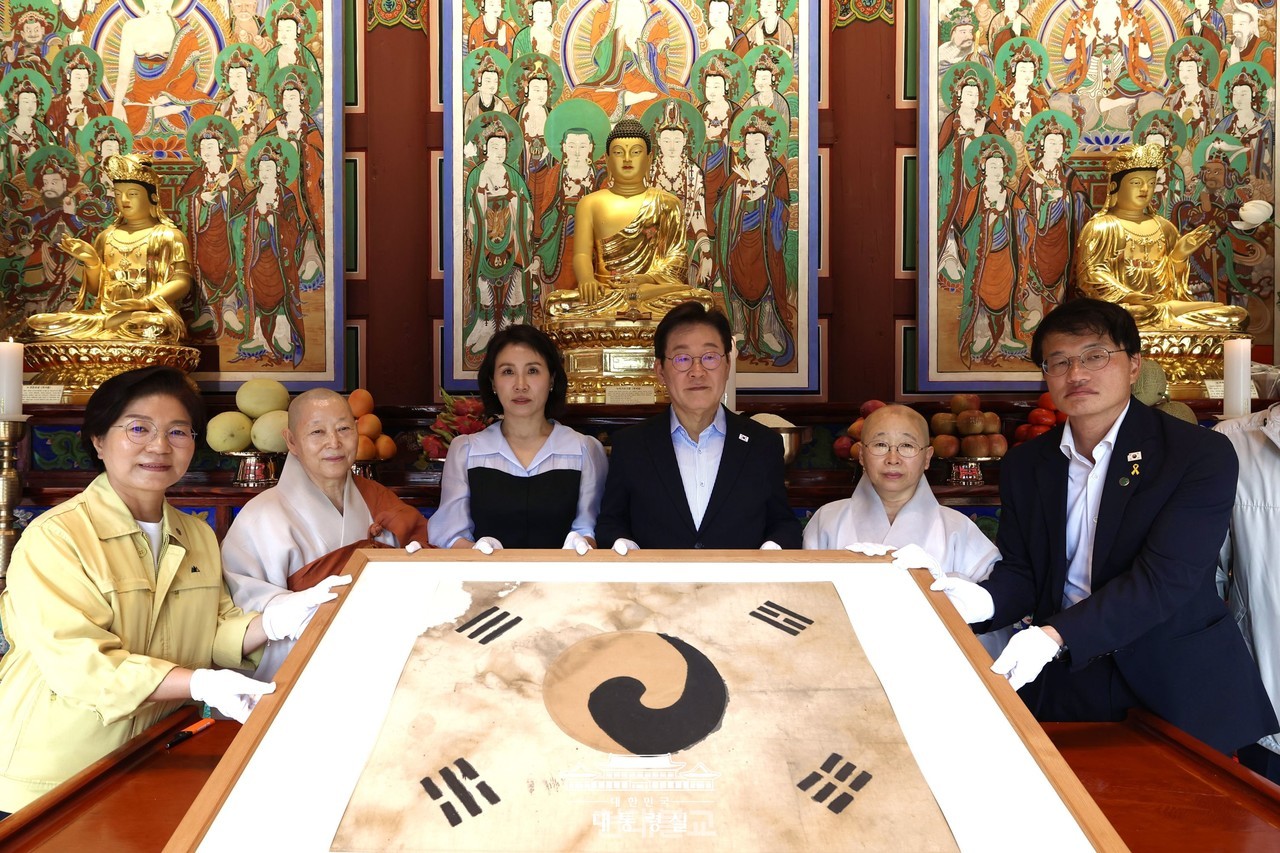 이재명 대통령이 8월 17일 서울 진관사를 방문해 “서로 갈라져 상처 입은 국민들을 잘 보듬고 끌어안아야 한다”고 말했다. 사진은  진관사 회주 계호 스님(왼쪽에서 두 번째), 주지 법해 스님(오른쪽에서 두 번째)과 함께 '진관사 태극기'를 들고 기념촬영하는 이 대통령 내외.  사진=대통령실.