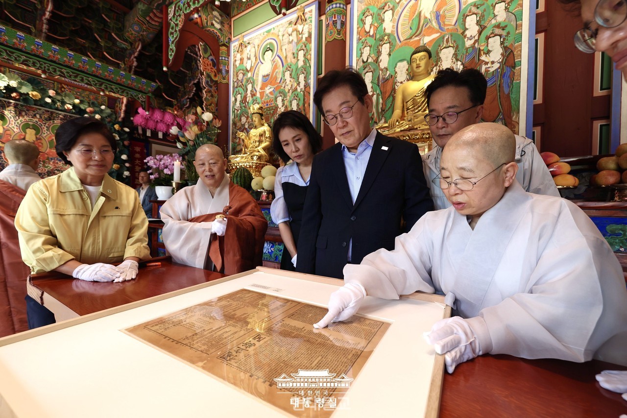 진관사 주지 법해 스님이  이재명 대통령 내외에게 '진관사 태극기'와 함께 발견된 독립신문에 대해 설명하고 있다. 사진=대통령실.