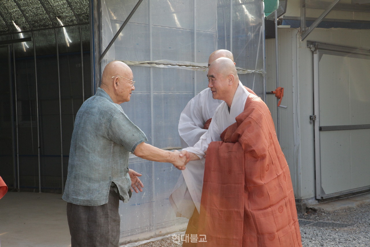 성파 스님이 총무부장 성웅 스님에게 악수를 건네며 격려하고 있다.