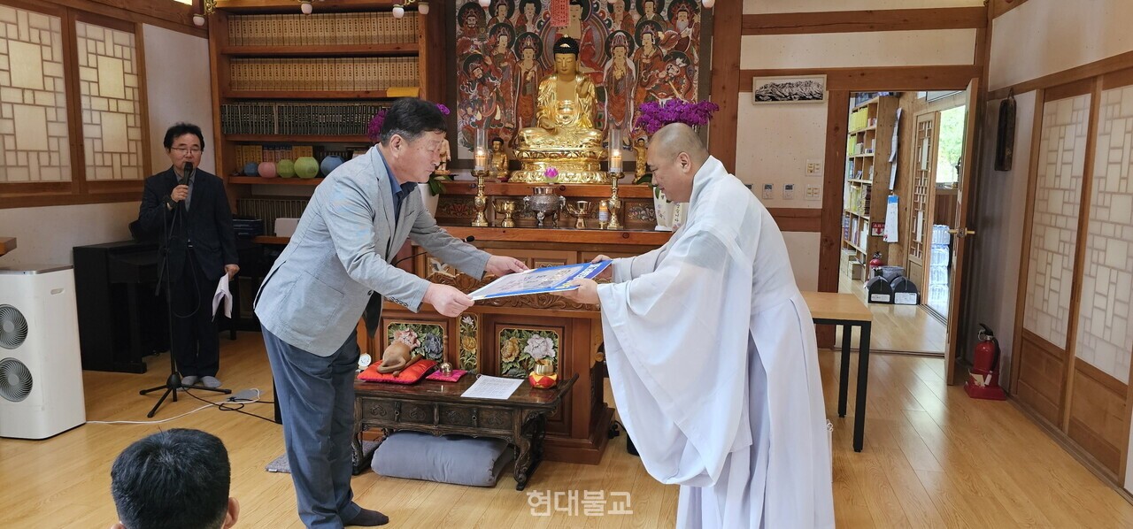 대현 스님이 변영국 고성군 국장에게 장학증와 자비의 쌀을 전달하고 있다.