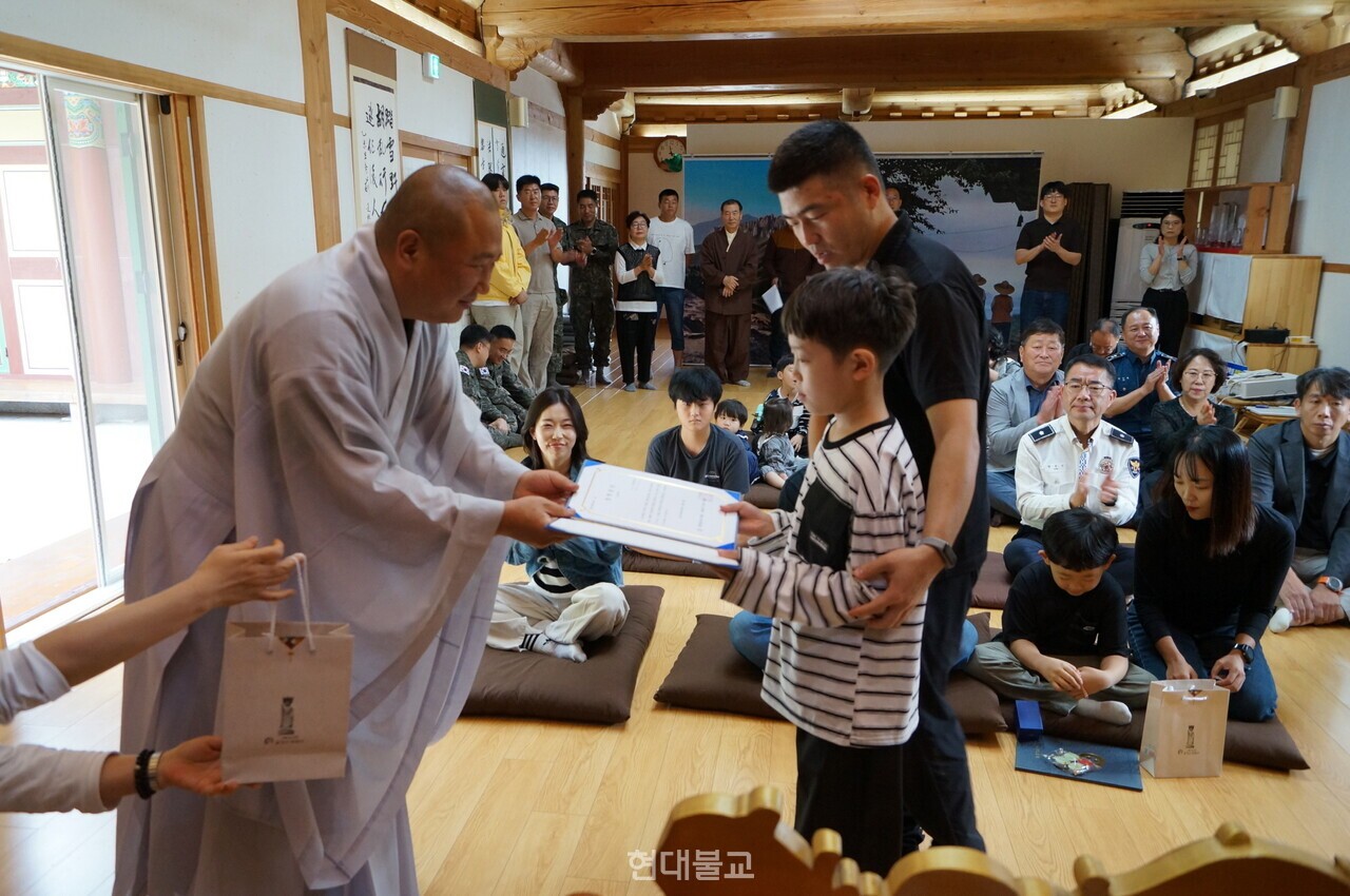 대현 스님이 어린이에게 장학증서와 선물을 전달하고 있다