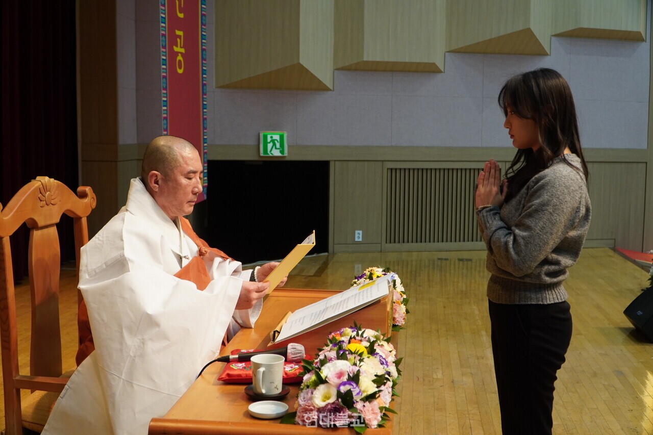 돈관 스님이 학생 대표 고수진 학생에게 계첩을 전달하고 있다. 