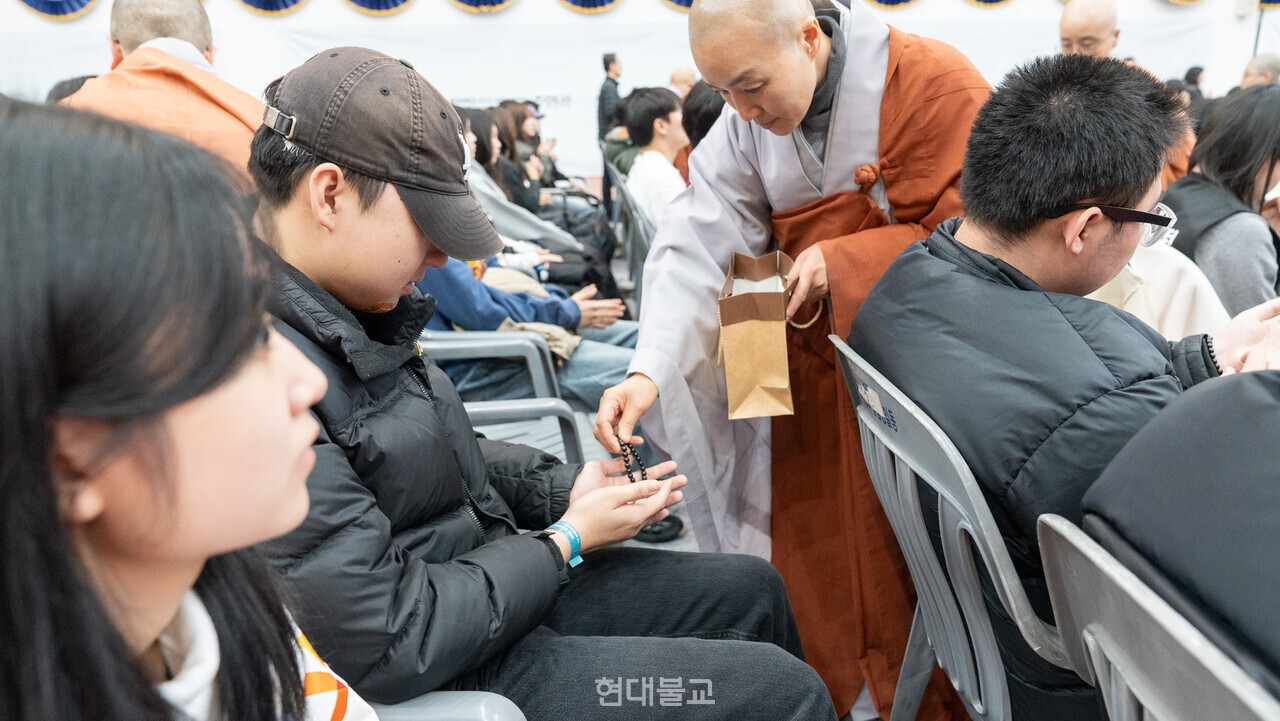 스님이 연비의식에서 청년불자에게 단주를 전달하고 있다.