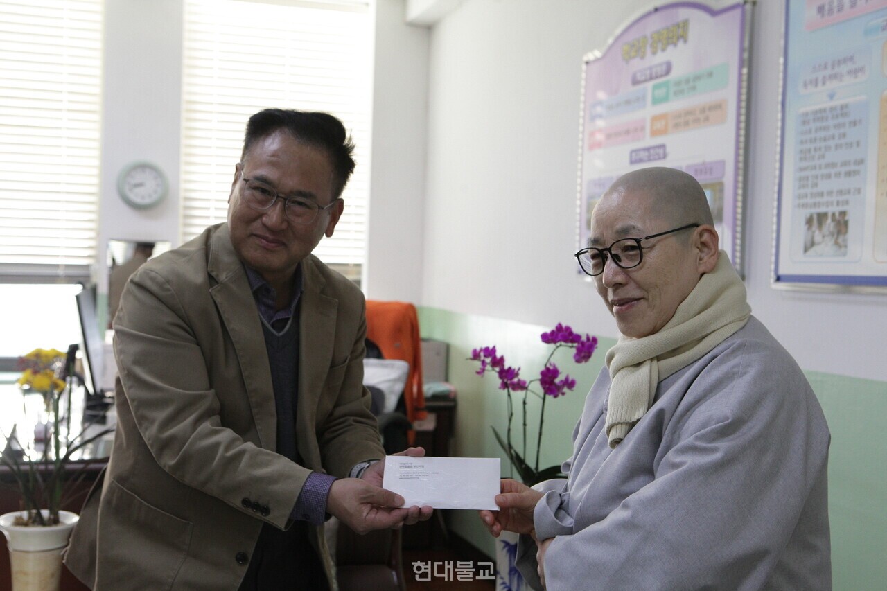 한마음선원 부산지원장 혜도 스님이 박용호 교장에게 후원금을 전달하는 모습.