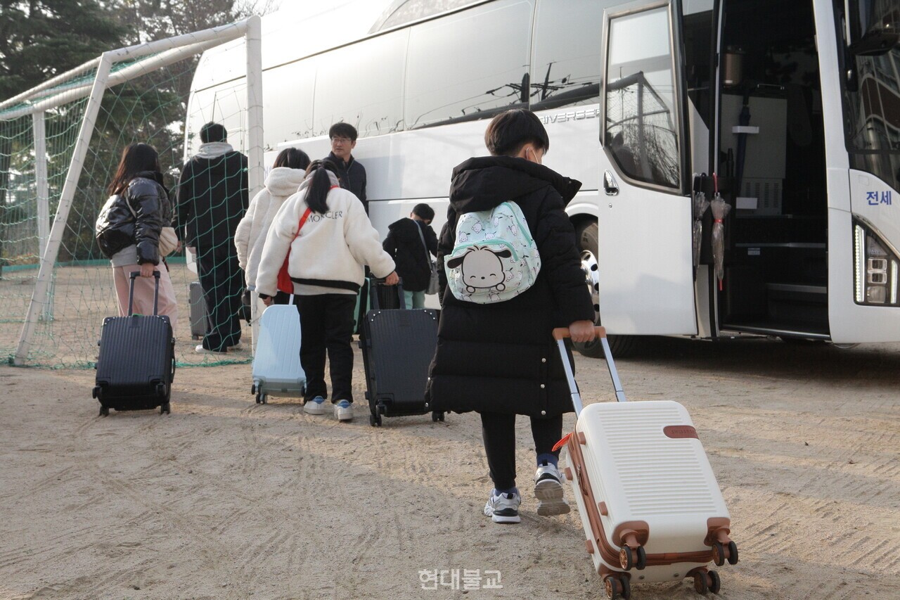 캐리어를 끌며 버스에 탑승하는 학생들의 모습.