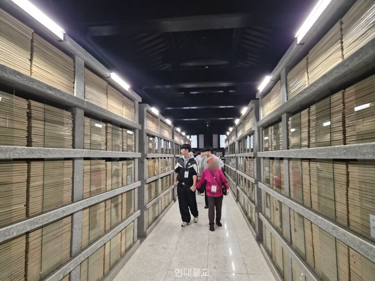 서운암 장경각에서 어르신의 손을 꼭 잡고 걸음을 맞추며 나란히 걷고 있는 학생의 모습.